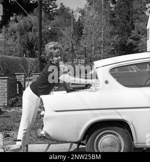 In den 1960er Jahren. Schauspielerin Lill-Babs wäscht ihr Auto, ein Ford Anglia. Ihre Mutter rechts. Schweden 1964 Stockfoto