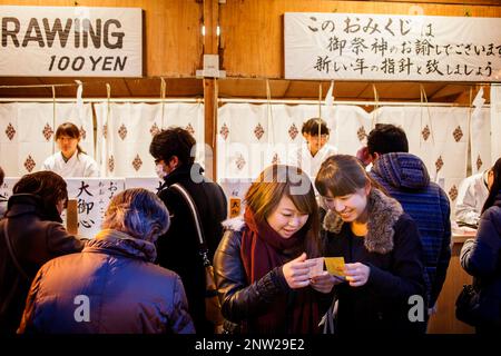 Mädchen lesen Omikuji Papier Orakel, während Hatsumode, ist der erste Shinto-Schrein besuchen das japanische Neujahr. Einige Leute besuchen einen buddhistischen Tempel ich Stockfoto