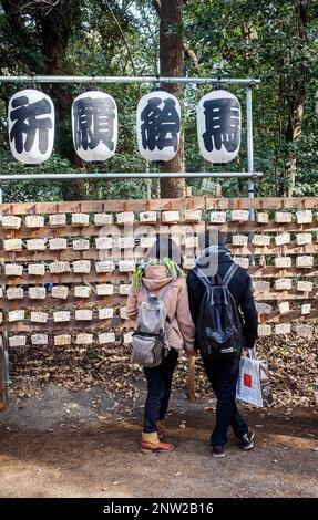 Paar lesen Holztafeln mit Gebete am Heiligtum Meiji Jingu, Tokyo, Japan Stockfoto