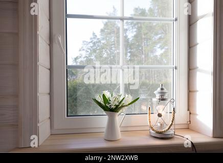 Weißes Fenster mit Mosuito-Netz in einem rustikalen Holzhaus mit Blick auf den Blütengarten. Stockfoto