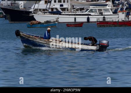 Zwei Fischer in einem kleinen Boot mit Außenbordmotor fahren vom Hafen von Porto Grande auf den Kap-verden-Inseln zu ihren atlantischen Angelplätzen. Stockfoto