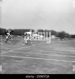 1950er, historisch, zwei männliche Wettbewerber, die an einem Sprint-Radrennen auf einer Grasstrecke in England, Großbritannien, teilnehmen. Grasrennen waren zu seiner Zeit eine beliebte Aktivität in Großbritannien, insbesondere an einem Pfingstmontag, an einem öffentlichen Feiertag oder an einem Feiertag Ende Mai. Stockfoto