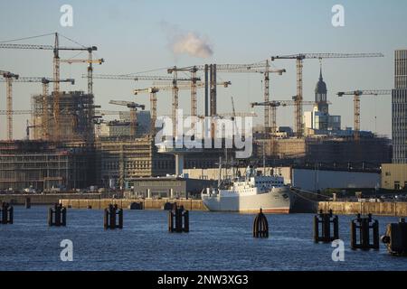 Hamburg, Deutschland. 06. Februar 2023. Die Kirche von St. Michaelis (Michel) ist zwischen den Kranen auf der Baustelle HafenCity zu sehen. Im Vordergrund liegt das Schiff "MS Stubnitz" in Baakenhafen, einem ehemaligen Kühl- und Transportschiff der Hochseefischerflotte der DDR, das heute als Veranstaltungsort genutzt wird. Auf der linken Seite sehen Sie den Kreuzfahrthafen Baakenhöft, einen alternativen Terminal für kleinere und mittelgroße Kreuzfahrtschiffe, und den weißen Turm „Lighthouse Zero“. Kredit: Soeren Stache/dpa/Alamy Live News Stockfoto