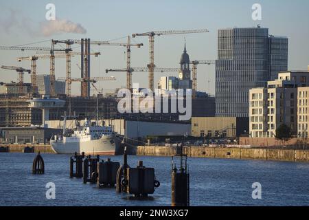 Hamburg, Deutschland. 06. Februar 2023. Die Kirche von St. Michaelis (Michel) ist zwischen den Kranen auf der Baustelle HafenCity zu sehen. Im Vordergrund liegt das Schiff "MS Stubnitz" in Baakenhafen, einem ehemaligen Kühl- und Transportschiff der Hochseefischerflotte der DDR, das heute als Veranstaltungsort genutzt wird. Auf der linken Seite sehen Sie den Kreuzfahrthafen Baakenhöft, einen alternativen Terminal für kleinere und mittelgroße Kreuzfahrtschiffe, und den weißen Turm „Lighthouse Zero“. Kredit: Soeren Stache/dpa/Alamy Live News Stockfoto