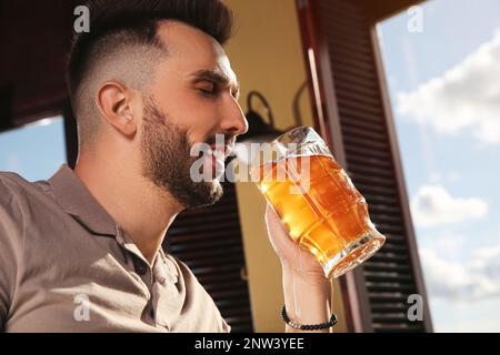 Bärtiger Mann, der im Pub leckeres Bier trinkt Stockfoto