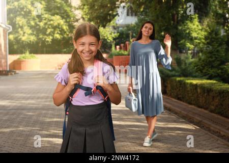 Mutter winkte ihrer Tochter vor der Schule im Freien zu Stockfoto