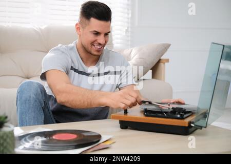 Glücklicher Mann, der zu Hause Musik mit Plattenspieler hört Stockfoto
