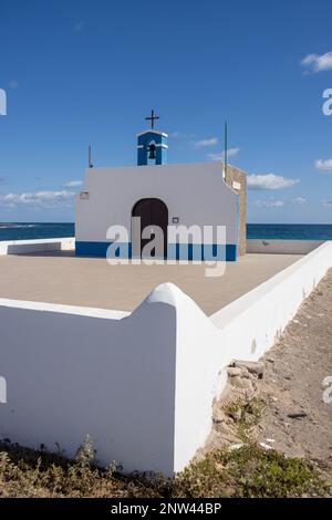 Kleine Kirche an der Ostküste des Atlantiks namens Ermita de la Virgen del Pino. Einfache Kombination aus Weiß und Blau. Glockenturm und Kreuz. Pue Stockfoto