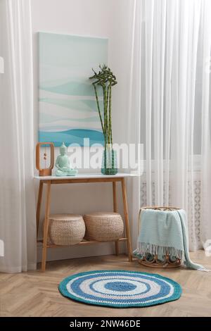 Konsolentisch mit Bambus- und Buddha-Statue in der Nähe von hellen Wänden im Innenbereich. Innendesign Stockfoto