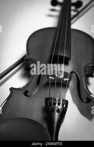 Schöne Geige und Schleife auf dem Tisch, Nahaufnahme. Schwarzweißtöne Stockfoto