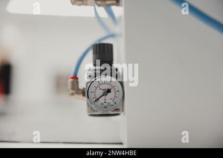 Ca-Nahaufnahme eines Manometers an einer weißen Wand in einer Fabrik Stockfoto