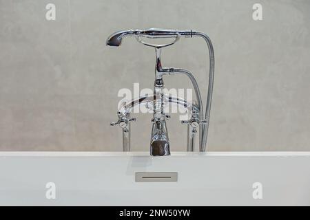 Silberner Wasserhahn im Retro-Stil in der Mitte der weißen Badewanne Stockfoto