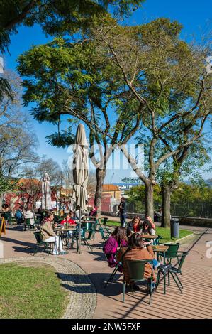 Die Menschen genießen einen sonnigen Tag auf einer Parkterrasse am Campo de Santa Clara, wo der Flohmarkt Feira da Ladra stattfindet, in Lissabon, Portugal Stockfoto