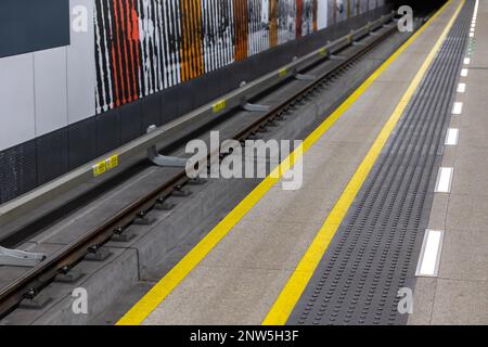 Gelbe Warnlinien auf U-Bahn- oder Bahnhofsplattformen. Sicherheitssysteme im städtischen Fußgängerverkehr Stockfoto