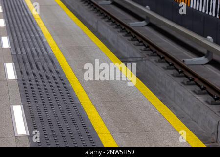 Gelbe Warnlinien auf U-Bahn- oder Bahnhofsplattformen. Sicherheitssysteme im städtischen Fußgängerverkehr Stockfoto