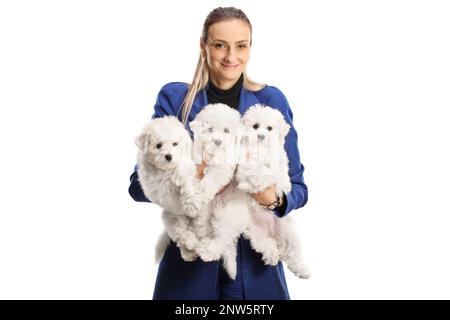 Eine Frau hält drei bichon-Frise-Welpen und lächelt isoliert auf weißem Hintergrund Stockfoto