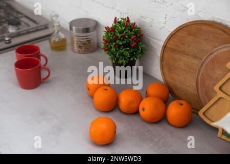 Konzeptionelle No-People-Aufnahmen von Mandarinen, Glückskeksen und farbigem Papier auf dem Tisch im Wohnzimmer, dekoriert für die chinesische Neujahrsfeier. Stockfoto