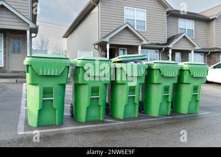 Horizontale Aufnahme von Eigentumswohnungen, Mülltonnen, die auf einen Kipplaster warten. Stockfoto