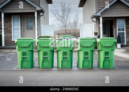 Horizontale Aufnahme von Eigentumswohnungen, Mülltonnen, die auf den Kipplaster warten. Stockfoto