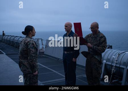 USA Annemarrie Guerra, eine Spezialistin für Gastronomie beim Kampflogistik-Bataillon 22, 26. Marine Expeditionary Unit, wird von Captain Gregory Baker, Kapitän des Amphibienschiffs USS Mesa Verde (LPD 19) der Klasse San Antonio, in ihren derzeitigen Rang befördert. Während Oberstleutnant Gregory Walker Oberstleutnant des Kampflogistikbataillons 22 (rechts) ihren Beförderungsbefehl während einer Zeremonie auf See am 1. Februar 2023 vorliest. Beförderungszeremonien sind eine bedeutende Errungenschaft in der Karriere eines Dienstleistenden und ein Beleg für sein Engagement, seine Fähigkeiten und seine Führungsqualitäten Stockfoto