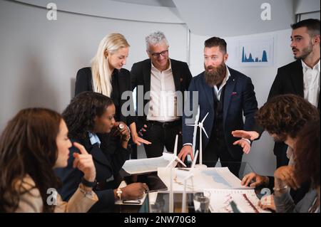 Gemischte Gruppe von Kollegen, die ein neues Projekt im Besprechungsraum diskutieren und planen. Stockfoto