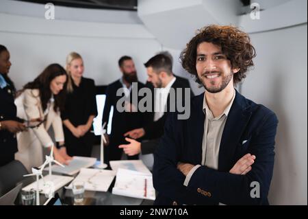 Porträt eines hipsterlächelnden Geschäftsmannes, der mit positivem Gesicht und gekreuzten Armen in die Kamera schaut. Teamarbeit am Arbeitsplatz. Stockfoto