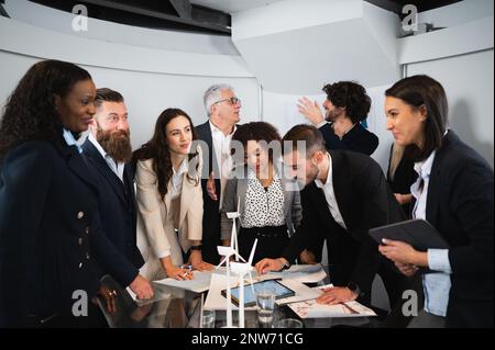 Große und multiethnische Gruppe von Kollegen Sin elegante Anzüge, die an einem nachhaltigen Projekt arbeiten. Geschäftsleute, die sich in einem Konferenzraum unterhalten. Stockfoto