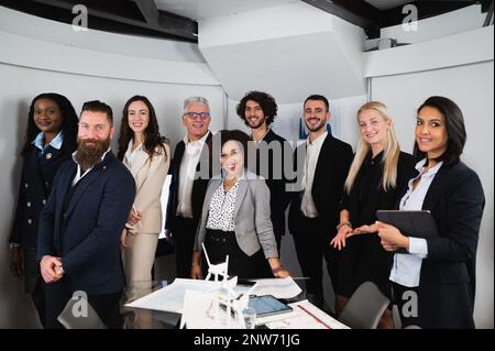 Eine Gruppe von Kollegen aus verschiedenen Rassen, die vor der Kamera stehen. Lächelnde Geschäftsleute in eleganten Anzügen. Stockfoto