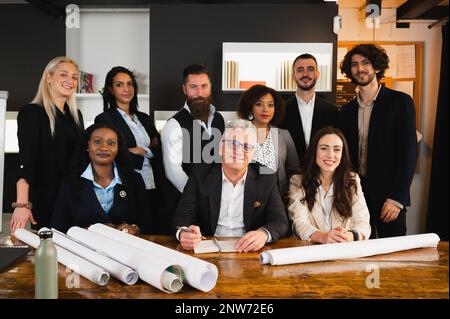 Portrait einer lächelnden Teamarbeit am Arbeitsplatz. Eine multiethnische Gruppe von Geschäftsleuten, die an einem Bauprojekt arbeiten. Stockfoto