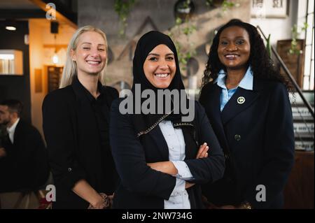 Porträt von drei eleganten Frauen unterschiedlicher ethnischer Herkunft, die vor die Kamera schauen. Stockfoto