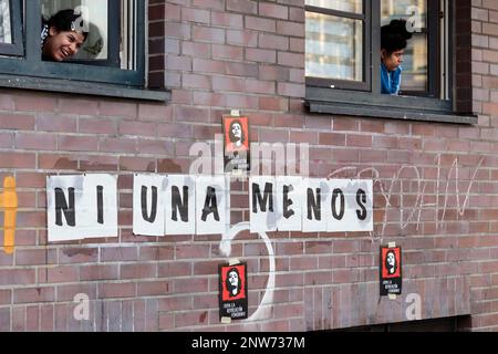 Berlin, Deutschland 3/8/2020 zwei junge Frauen lehnen sich aus dem Fenster des Gebäudes mit einem Schild auf Spanisch, auf dem "ni una menos" steht (nicht eine weniger) Frauentag 8M Stockfoto