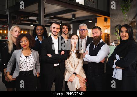 Große Gruppe von Kollegen posieren. Elegante Geschäftsleute mit unterschiedlichem Alter und unterschiedlicher ethnischer Herkunft Stockfoto