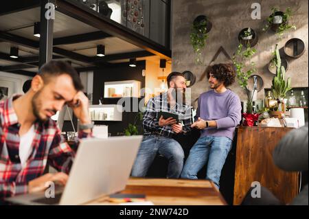 Zwei Hipster-Männer diskutieren über die Strategie eines neuen Startups. Gelegenheitsarbeiter, die in einem modernen Büro arbeiten. Stockfoto