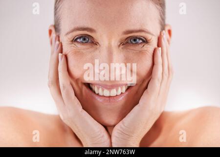 Shes noch strahlend schön. Studioportrait einer glücklichen reifen Frau, die mit dem Kopf in den Händen posiert. Stockfoto