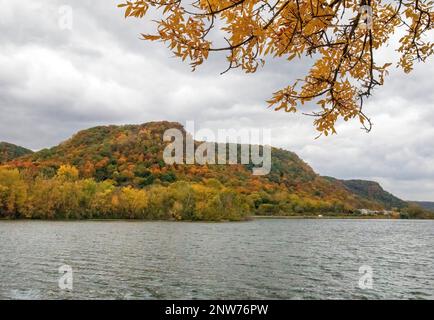 West Lake Winona mit seinen Klippen und Bäumen, die an einem wolkigen Herbsttag in Winona, Minnesota, USA, ihre Herbstfarben zeigen. Stockfoto