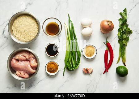 Gelber gebratener Curryreis mit Hühnerzutaten: Huhn, Reis, Fischsoße, Limette, Ei, Currypulver, Zwiebeln, Koriander, Chili, Knoblauch und Gewürze. Stockfoto