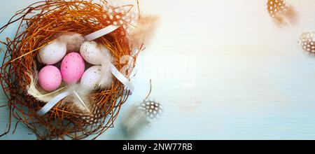 Kreatives flaches osterdesign mit ostereiern und dekorativem Nest auf blauem Tisch Stockfoto