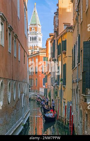 Gondoliere in traditionellen Gondeln nehmen Touristen mit auf Besichtigungstouren entlang der engen Kanäle in Venedig, Venetien, Nordostitalien Stockfoto