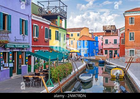 Farbenfrohe Restaurants und farbenfrohe Häuser entlang des Kanals von Burano, der Insel in der Lagune von Venedig, Venetien, Norditalien Stockfoto