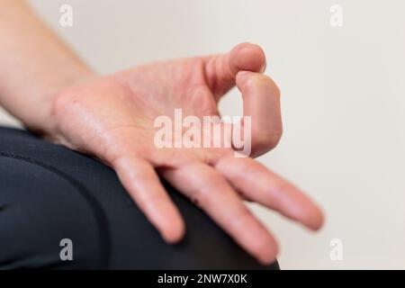 Horizontale Nahaufnahme der linken Hand von Yogini in der Chin Mudra-Geste, auch bekannt als Gyan Mudra, die Zeigefinger und Daumenhand nach oben verbindet Stockfoto