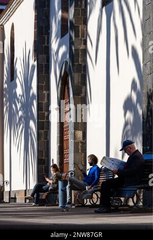 Menschen genießen die warme Wintersonne Teneriffas an der Kirche der Unbefleckten Empfängnis auf der Plaza Doctor Olivera San Cristobal de La Laguna. Stockfoto