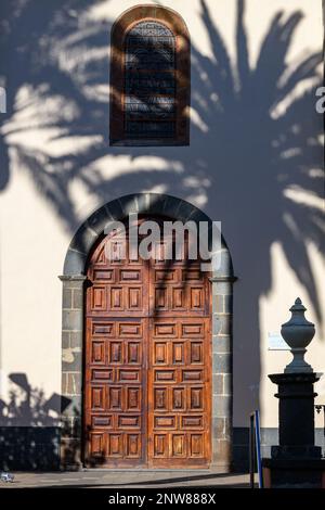 Am späten Nachmittag wirft die Sonne Schatten von Palmen auf die Wand der Kirche der Unbefleckten Empfängnis in San Cristobal de la laguna, Teneriffa. Stockfoto