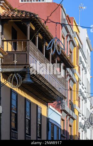 Ein archetypischer kanarischer Holzbalkon befindet sich im zweiten Stock eines lebhaften gelben Gebäudes in der Calle Herradores, San Cristobal de la Laguna Stockfoto