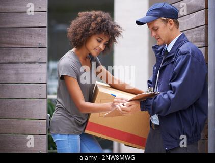 Lieferung direkt an Ihre Tür. Aufnahme eines Kuriers, der eine Lieferung an einen lächelnden Kunden abgibt. Stockfoto
