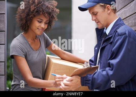 Lieferung direkt an Ihre Tür. Aufnahme eines Kuriers, der eine Lieferung an einen lächelnden Kunden abgibt. Stockfoto