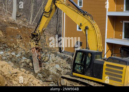 Hydraulikbagger mit Presslufthammer, ein Hydraulikbagger, der an einem Steinhaufen für den Straßenbau arbeitet Stockfoto