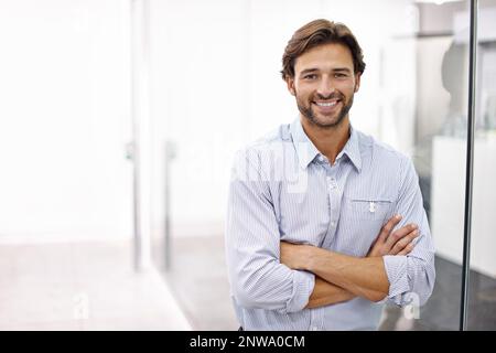 HES ein selbstbewusster junger Geschäftsmann. Porträt eines hübschen jungen Geschäftsmannes, der in seinem Büro steht. Stockfoto