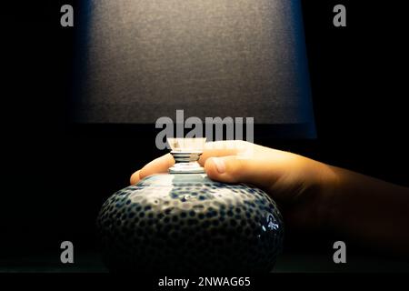 Nachttischlampe im Lieferumfang enthalten, die im Dunkeln leuchtet und von einem Kind in der Hand gehalten wird, Lampe im Retro-Stil Stockfoto