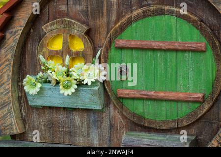 Fabelhaftes kleines Kinderhaus in einem Baumstamm in einem Park im Sommer in der Sonne in der Ukraine, ein Haus für einen Zwerg, ein Haus aus einem Märchen Stockfoto