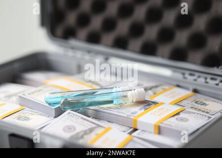 Chemisches Medikament im Kolben auf Packungen mit Dollar im Koffer Stockfoto